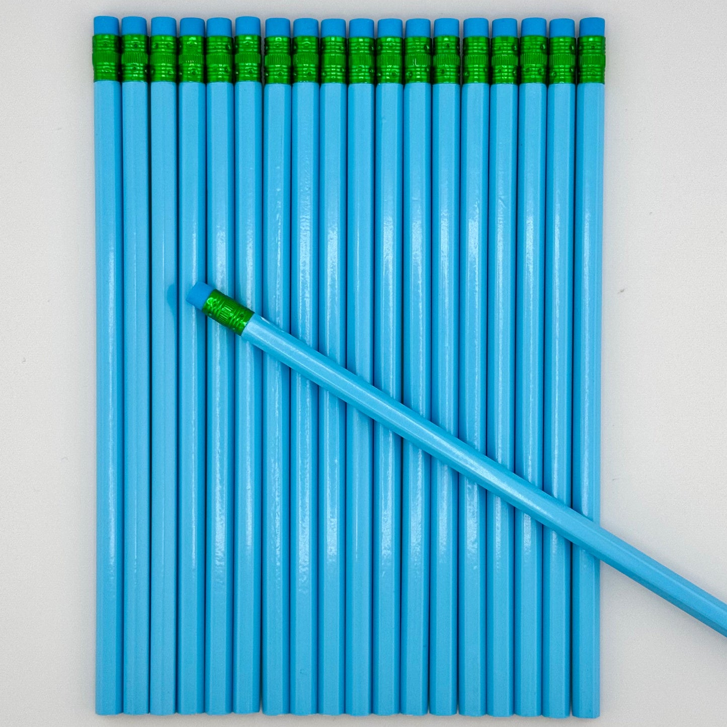 Blue pencils with blue erasers arranged on a light gray background