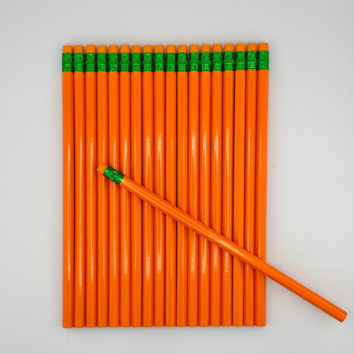 Stack of orange pencils with orange erasers on a white background