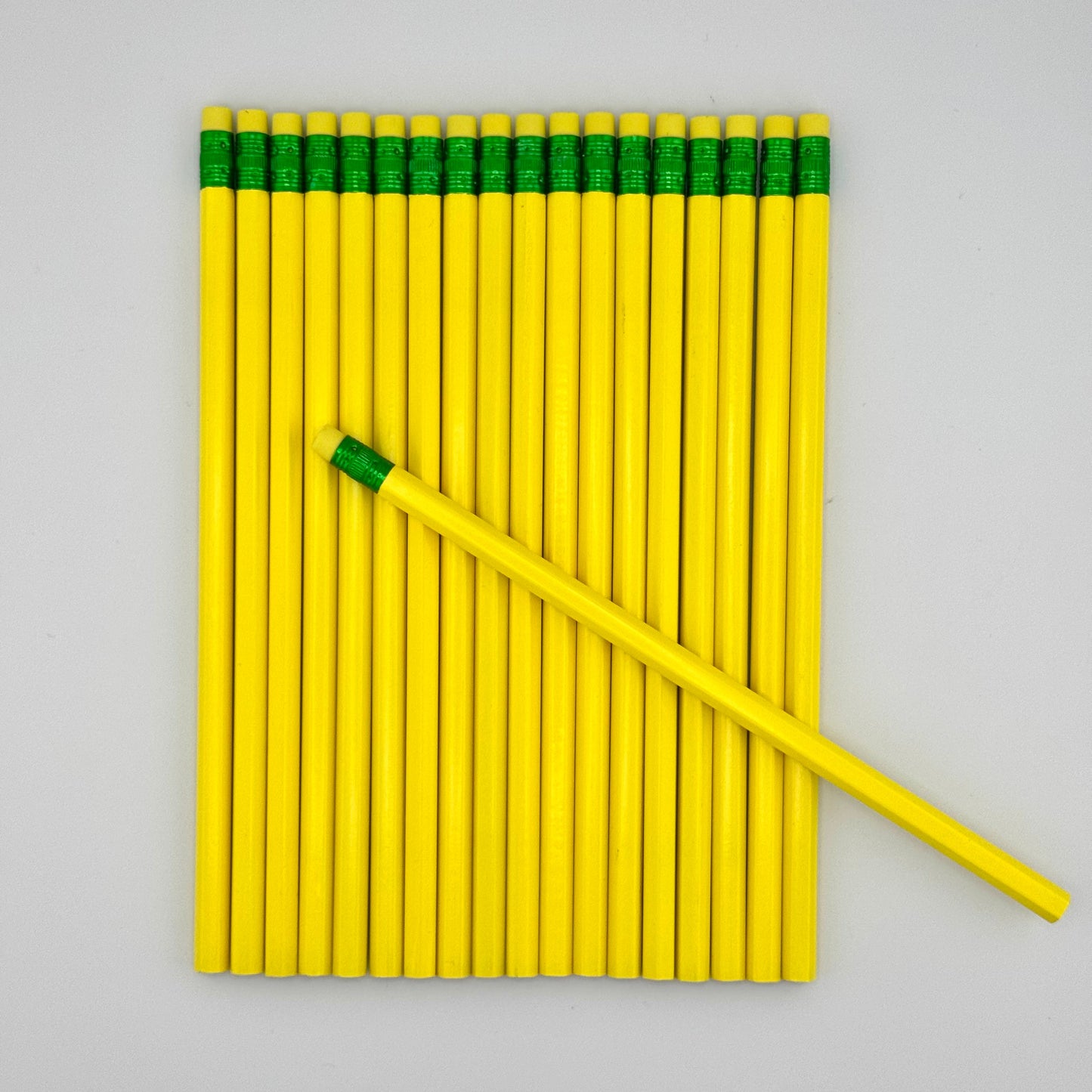 Yellow pencils with green caps arranged on a gray background