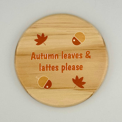 Wooden coaster with autumn-themed design and text on a light gray background