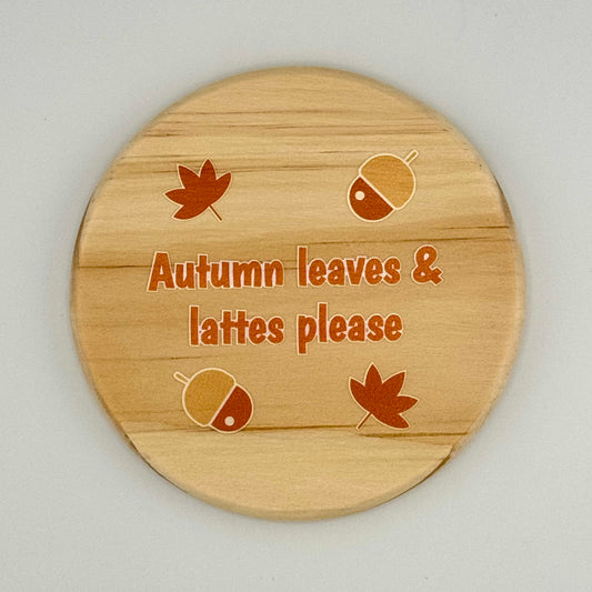 Wooden coaster with autumn-themed design and text on a light gray background