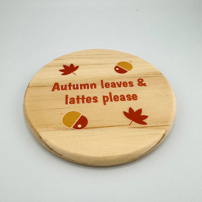 Wooden coaster with autumn-themed design and text on a light gray background