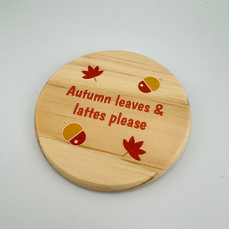Wooden coaster with autumn-themed design and text on a light gray background