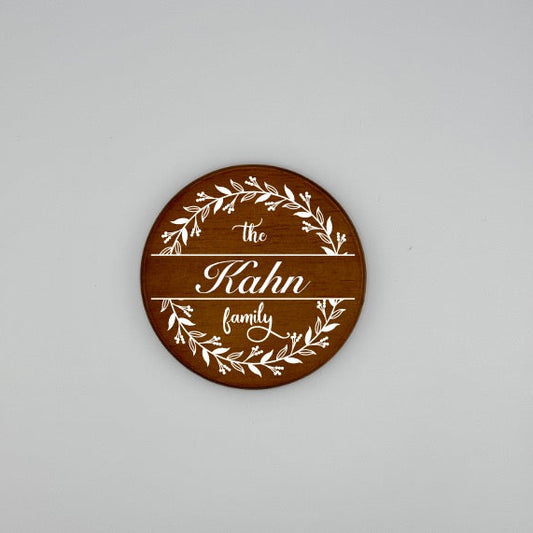 Round wooden plaque with 'the Kahn family' engraving on a gray background